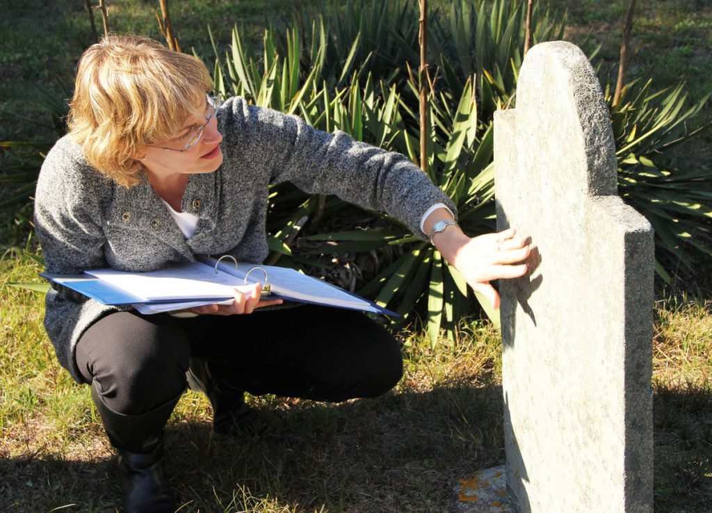 The Historical Commission's Jennifer Madden inspects a headstone at Cedarville Cemetery (CREDIT: Karen B Hunter -Enterprise